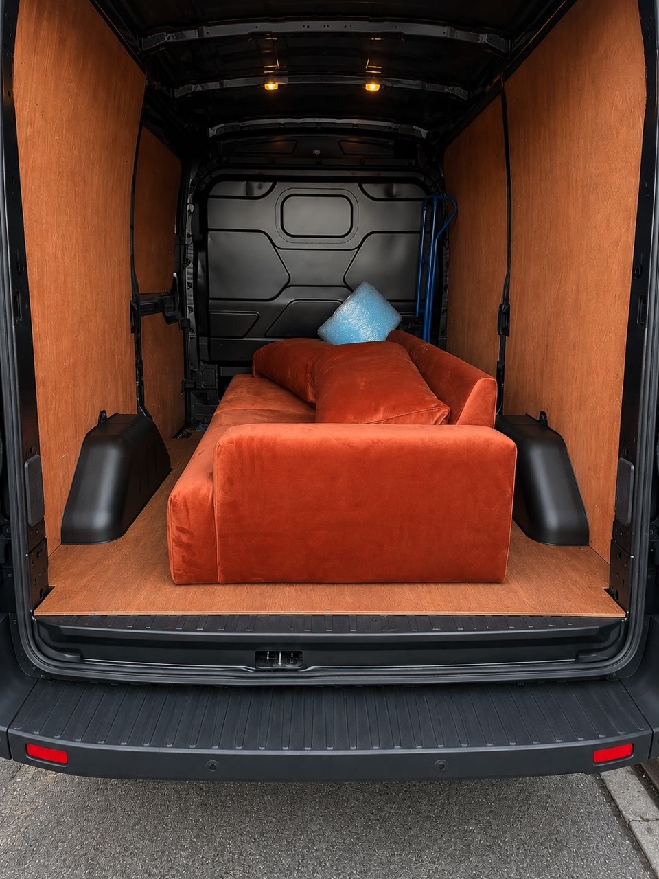 Orange sofa loaded into a clean wood-lined van